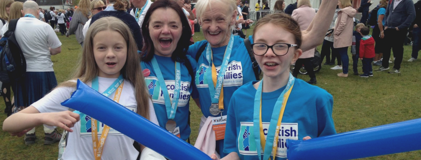 A photo of two women and two young girls cheering at the Glasgow Kiltwalk for Scottish Families